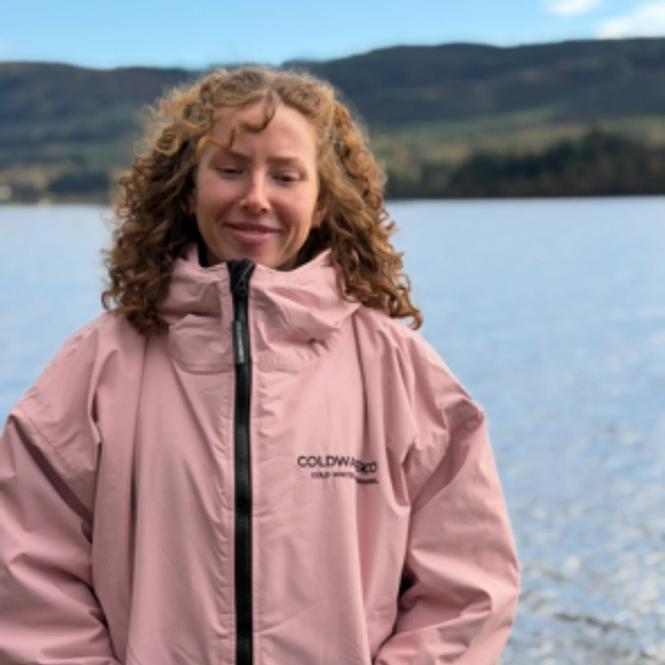 Woman in pink changing robe by the water