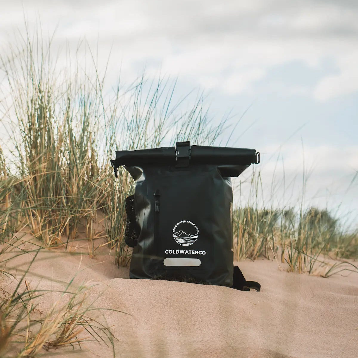 Black bag with a brand logo on sand dunes