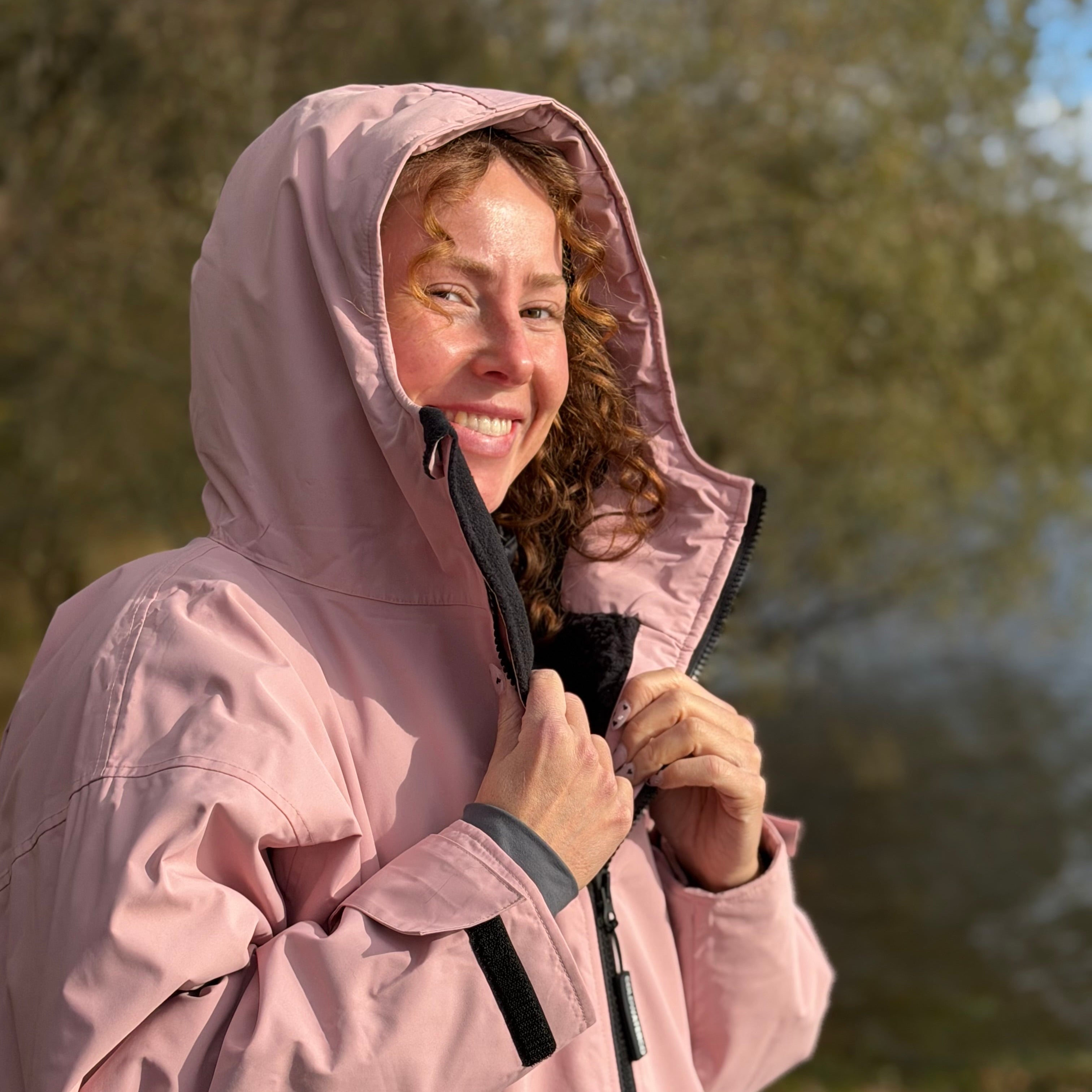 Person wearing a pink raincoat outdoors with trees in the background