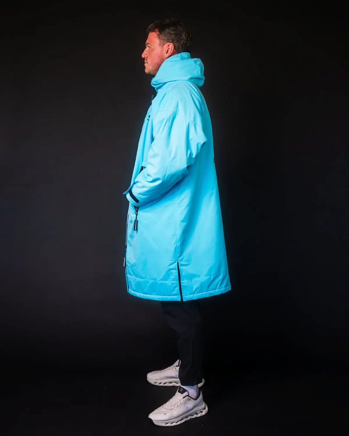 Man in blue ColdWaterCo changing robe with dark background