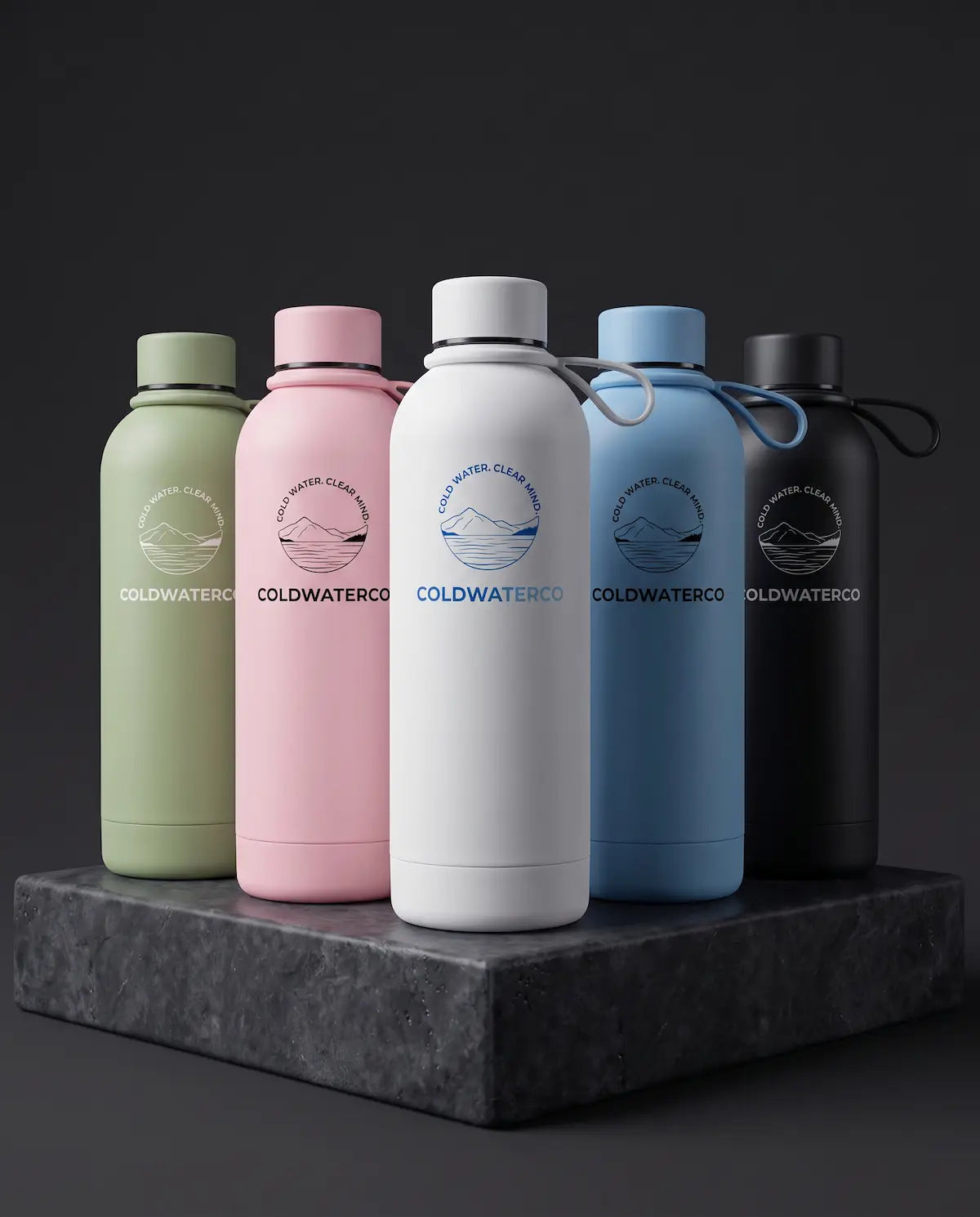 Five insulated water bottles from Coldwater Co are lined up on a dark stone pedestal against a dark gray background. The bottles are in sage green, pastel pink, white, light blue, and matte black, each featuring the brand's circular logo and name printed on the front.