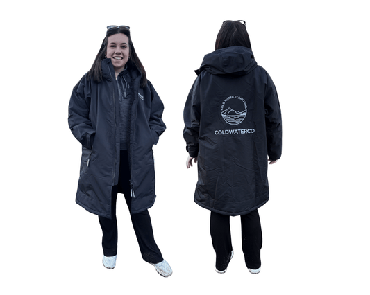 Woman wearing a black ColdWaterCo changing robe with a visible brand logo on a white background