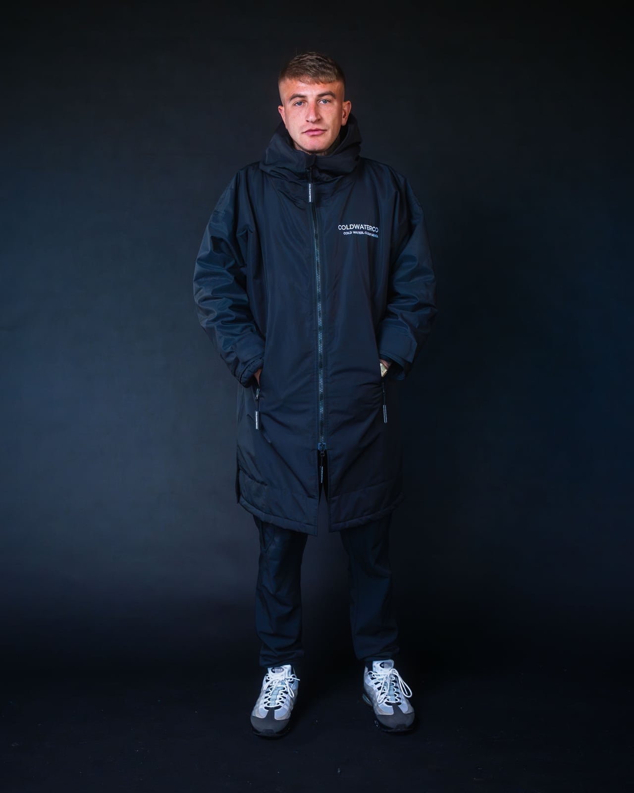 Man wearing a black coldwaterco robe with a brand logo on a black background