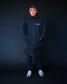 Man wearing a black coldwaterco robe with a brand logo on a black background