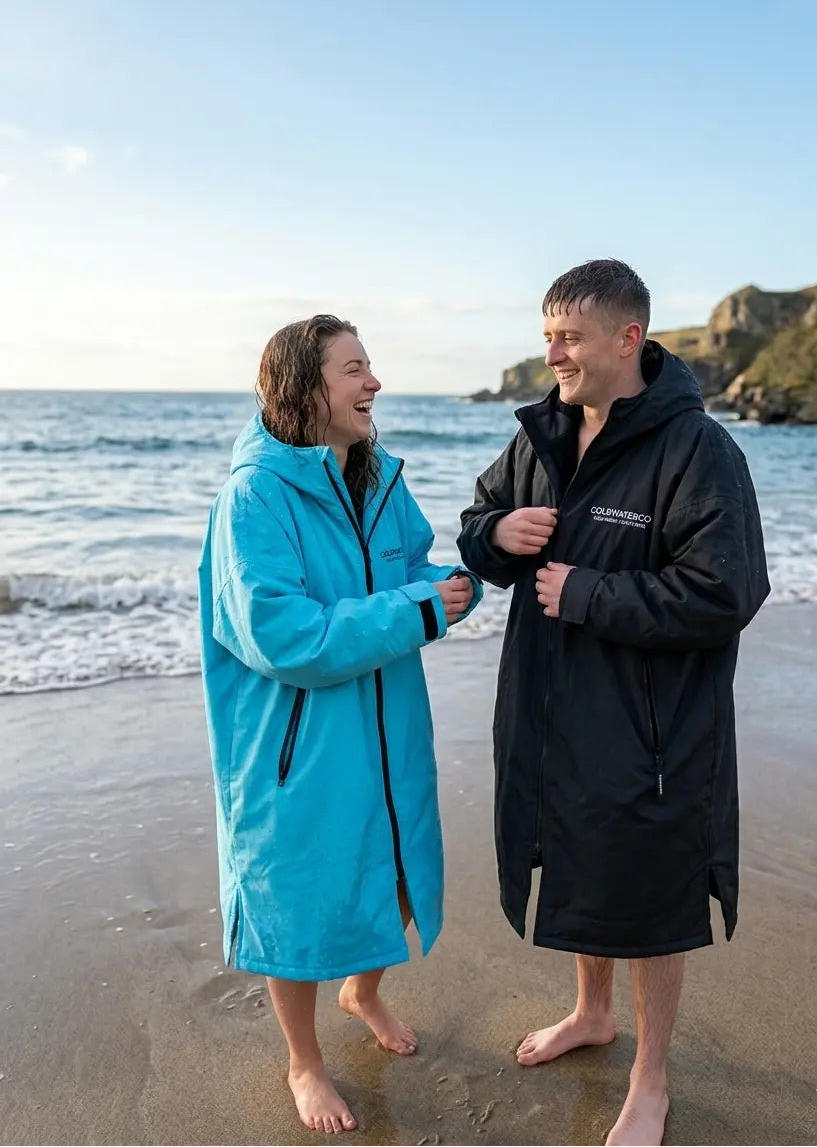Two people wearing waterproof jackets on a beach with ocean and sky in the background