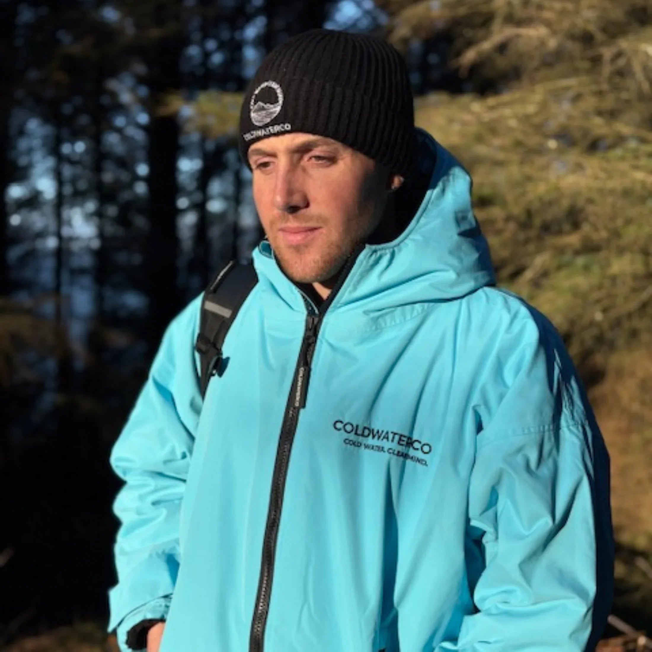 Person wearing a light blue jacket with 'Coldwater Co' branding outdoors.