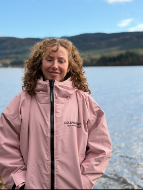 Woman in pink changing robe by the water