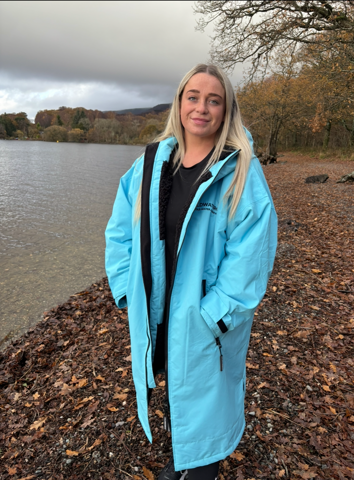 Woman in blue changing robe by some water