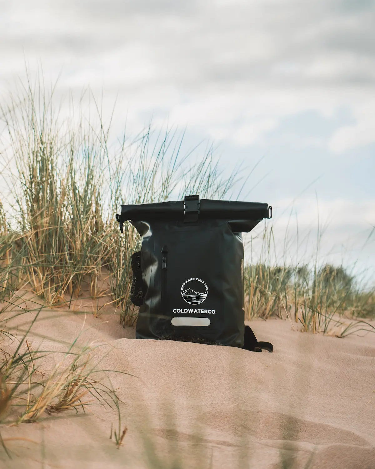 Black bag with a brand logo on sand dunes
