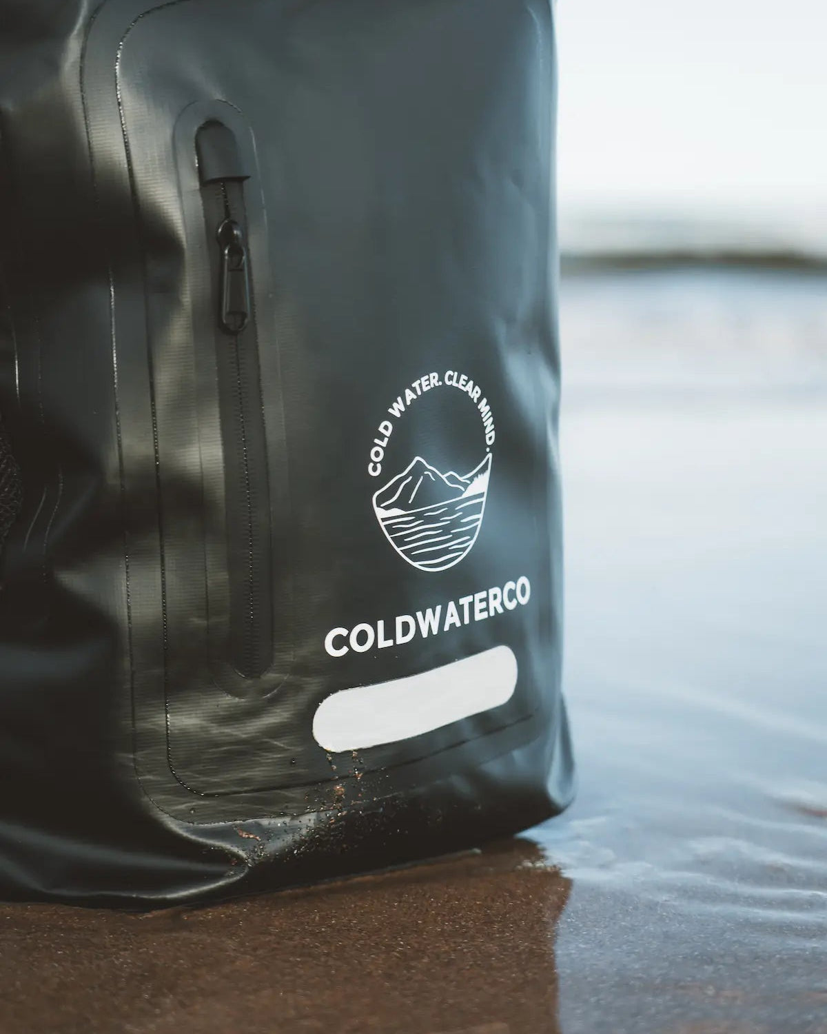 Black backpack with 'Coldwater Co' logo on a reflective surface