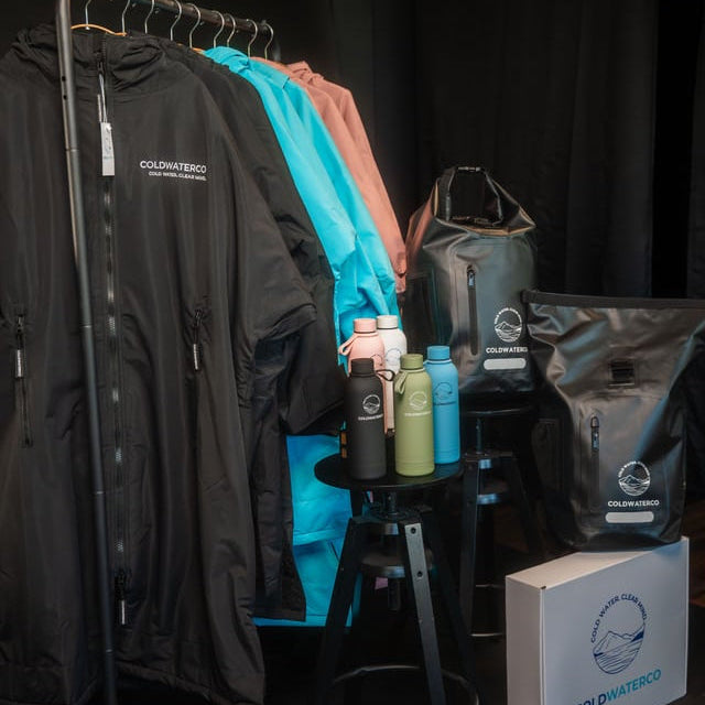 Clothing rack with jackets, bottles, and a box on a dark background