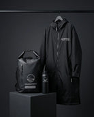 Black raincoat, backpack, and water bottle with 'Coldwater Co.' branding on a dark background.