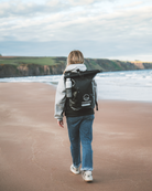 Person walking on a beach with a backpack