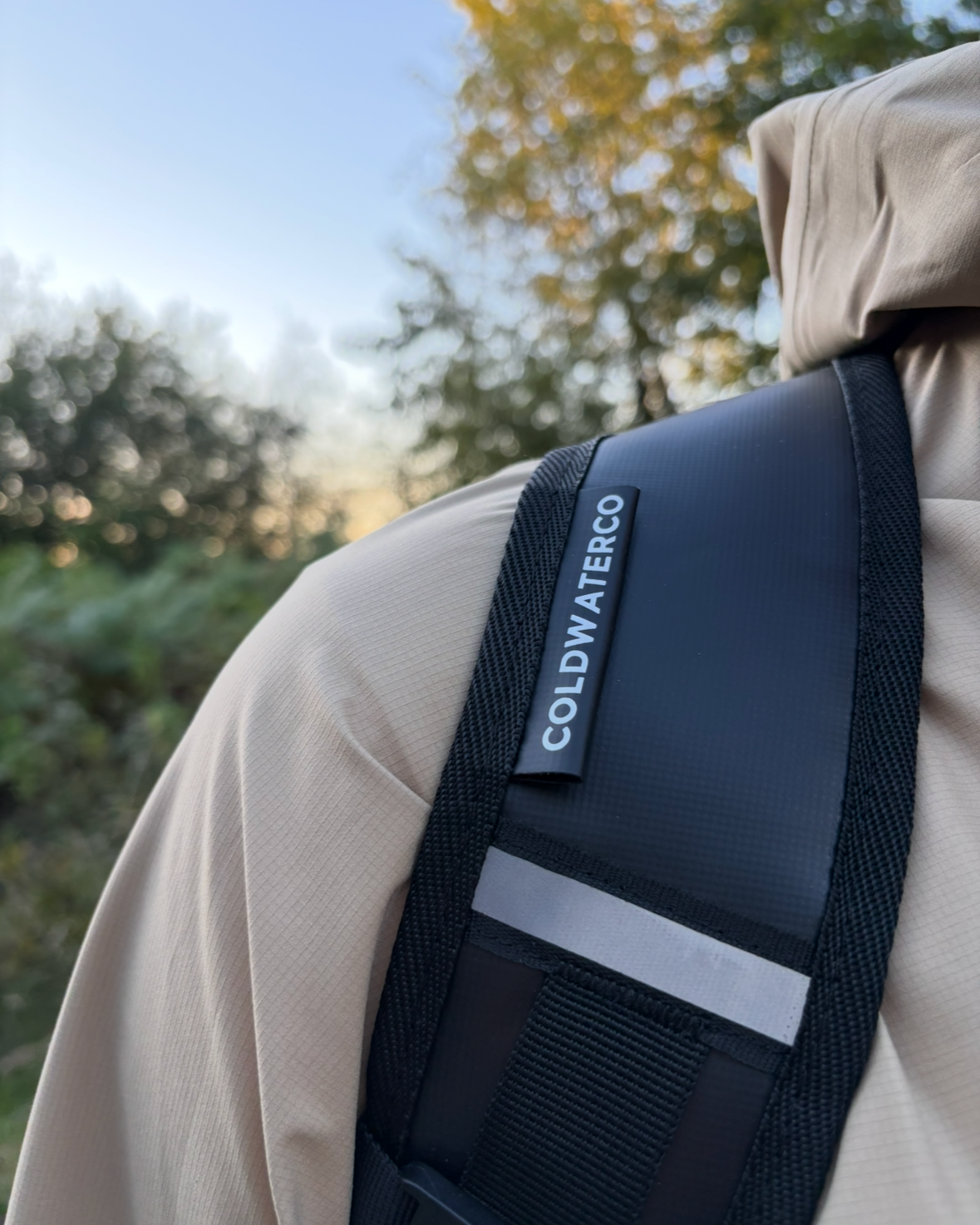 black backpack strap with branded coldwaterco tag and reflective strip. 