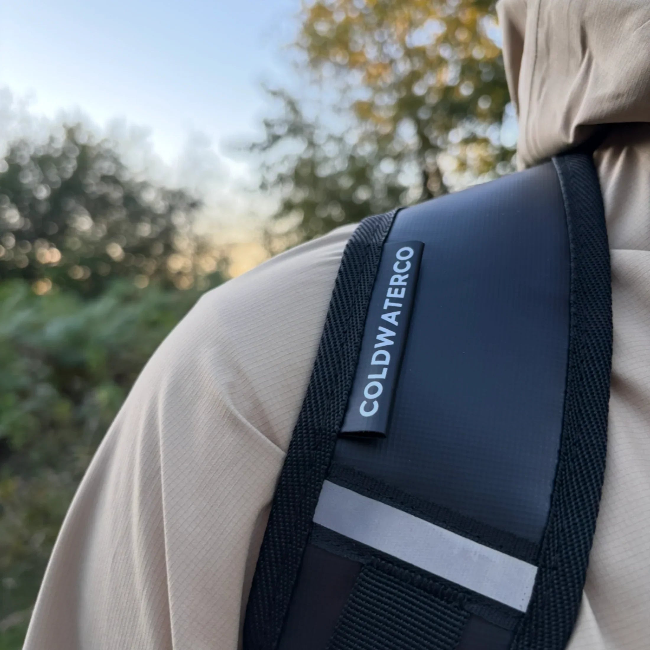 black backpack strap with branded coldwaterco tag and reflective strip. 