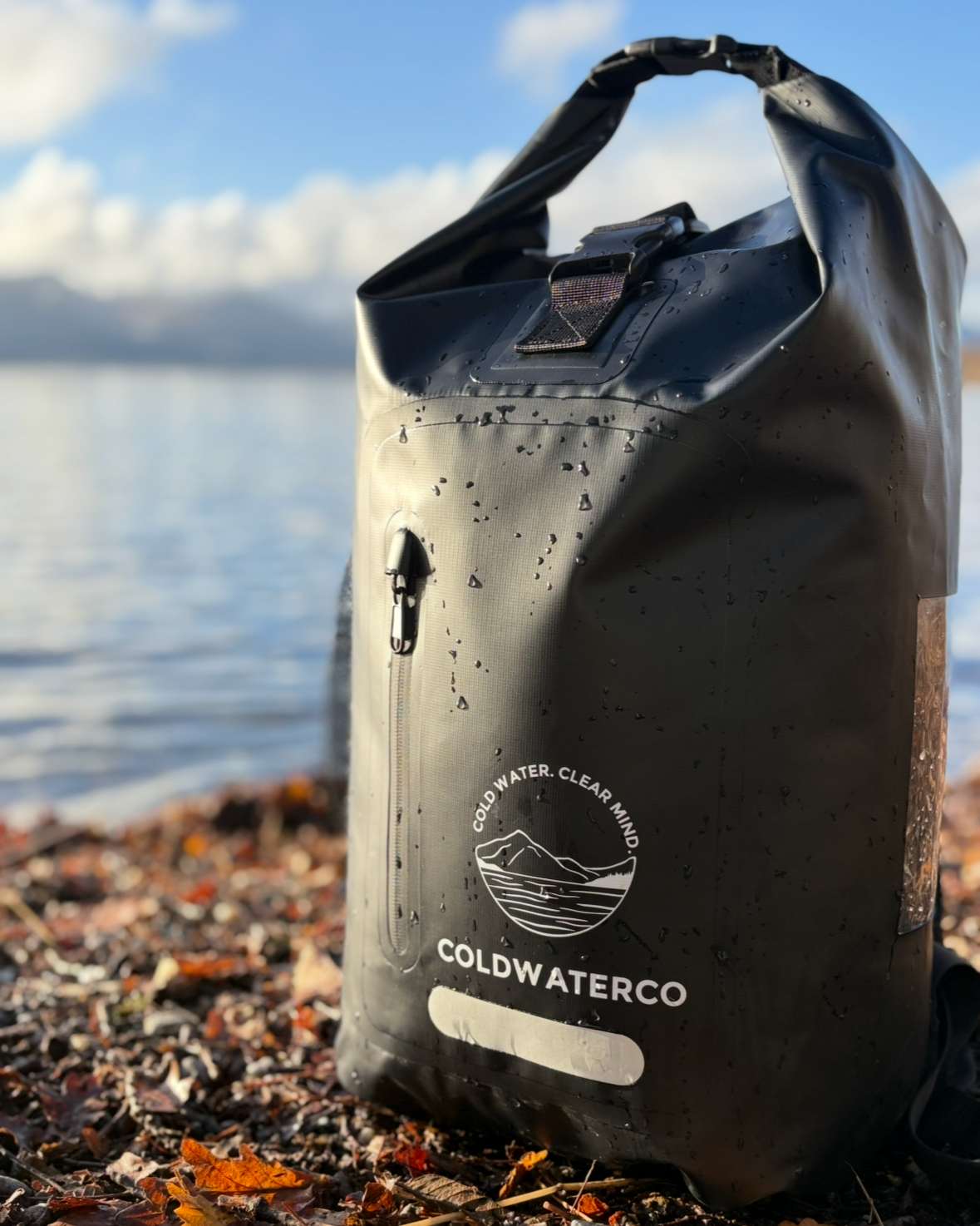 Black waterproof bag with 'Coldwater Co' logo on a beach