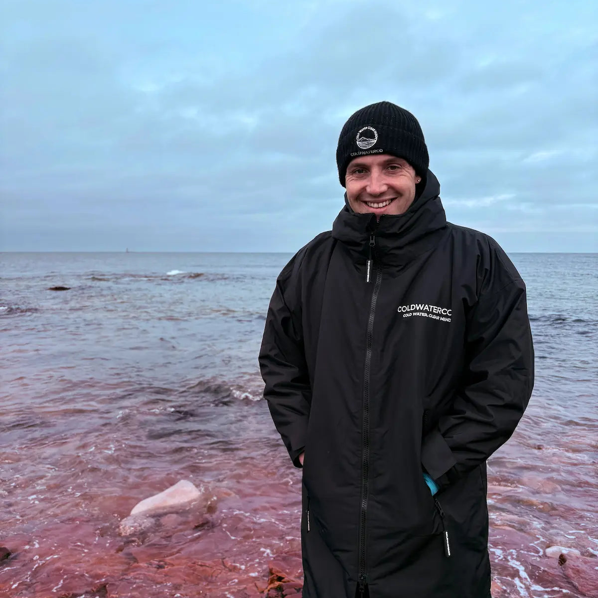 PErson smiling in ColdWaterCo robe at the waters edge