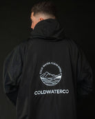 Person wearing a black jacket with ColdwaterCo logo on the back against a dark background
