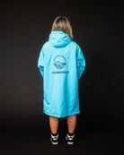 Person wearing a bright blue raincoat with a visible brand logo on the back against a black background