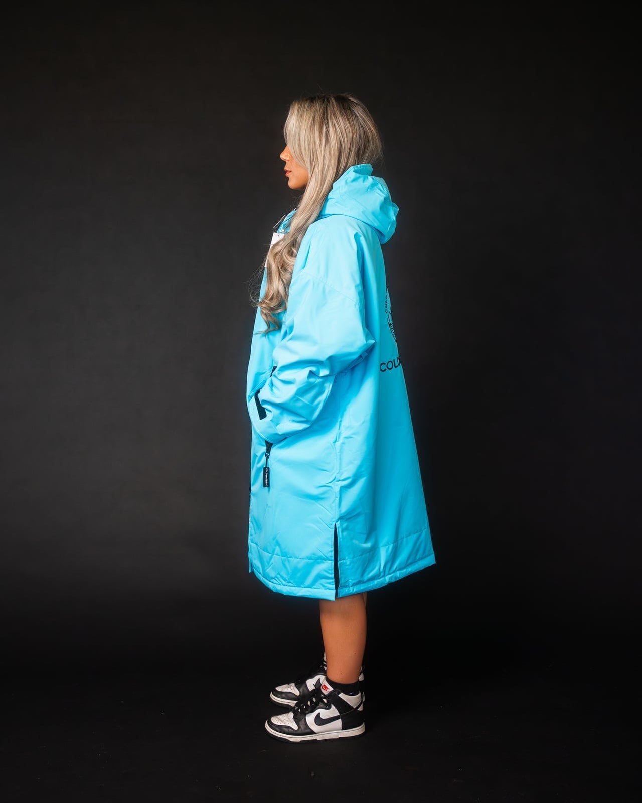 Person wearing a bright blue raincoat on a black background