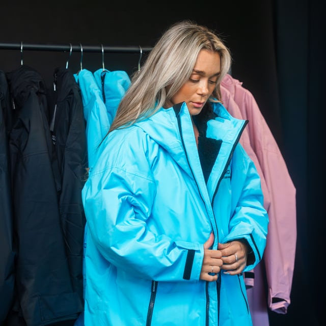 Person wearing a bright blue coat in a clothing store setting
