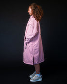 Person wearing a pink coat standing against a black background