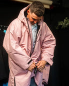 Person wearing a pink coat with a dark background