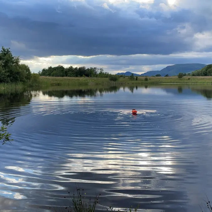 Lady swimming in middle of a loch with a float