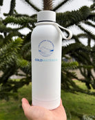White water bottle with 'Cold Water Co.' branding held in front of green foliage